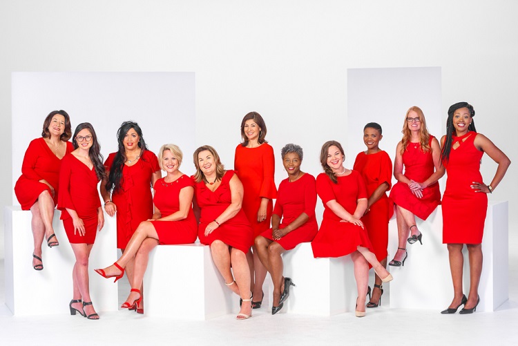 A group of eleven women wearing red dresses